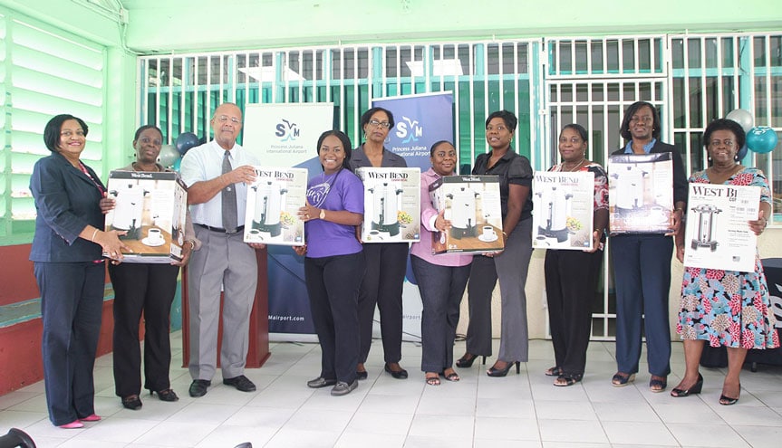 SXM Managing Director, Regina LaBega (first from left) and Acting Chairman of the Supervisory Board of Directors, Cleavland Beresford (3rd from left) join the school managers and Head of Public Education, Mrs. Glenderlin Davis-Holiday (2nd from right) in posing with the milk/tea dispensers presented to the public schools Friday. (SXM Airport photo)