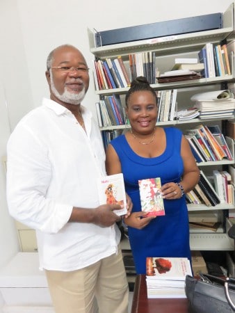 Hon. Louis Mussington (L), presents books published in St. Martin to Marie Michele Raymond, Head of the legal deposit of the National Library of Haiti. While in Port-au-Prince Mussington attended CARIFESTA XII activities, August 21 – 30, 2015. (© CLF photo)