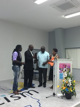 Dr. Quince Duncan (2nd r) is about to receive the Presidents Award of the St. Martin Book Fair 2016 from book fair coordinator Shujah Reiph, while Mrs. Jacqueline Sample (r), president of House of Nehesi Publishers, explains that the ebony statue was made in Nigeria. Looking on is Dr. Francio Guadeloupe, president of the University of St. Martin. (Photo courtesy: C. Davis-Kahina)